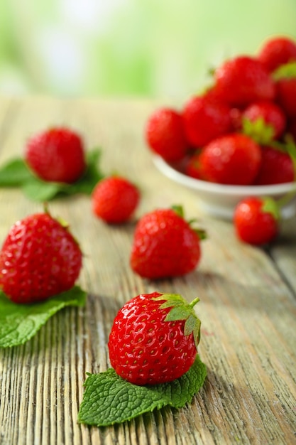 Fraises mûres dans une soucoupe sur une table en bois sur fond flou