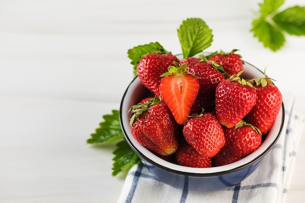 Fraises mûres fraîches dans un bol sur des écoproduits de fond blanc