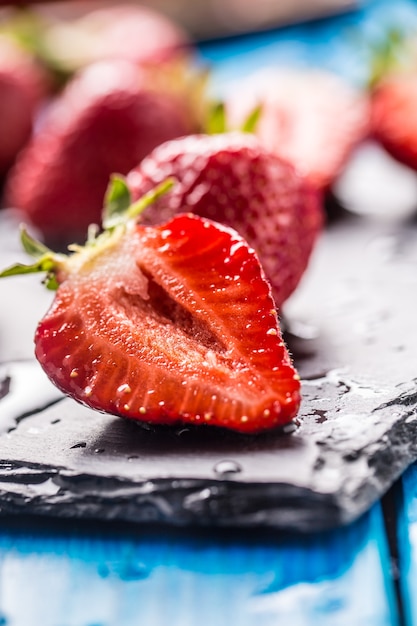 Photo fraises mûres fraîches lavées à l'eau sur table bleue.