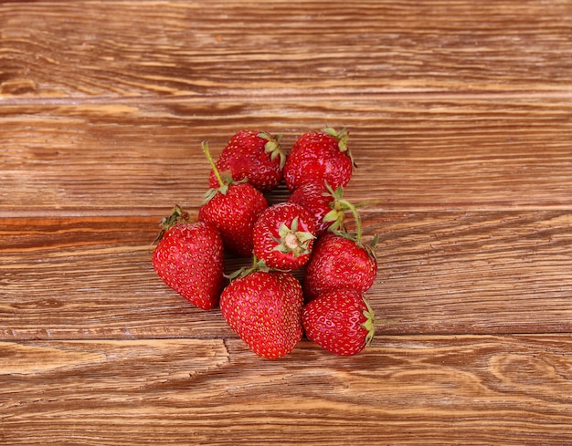 Fraises mûres, isolées sur fond de bois. Vue de dessus