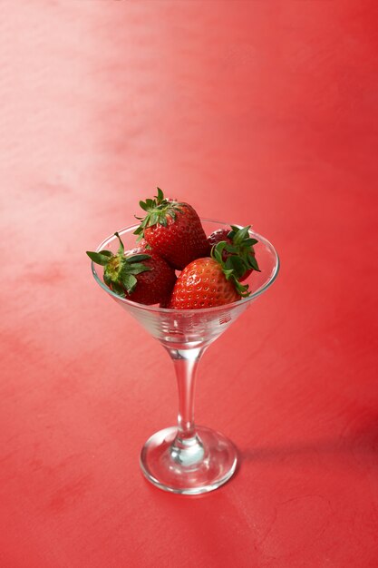 Fraises mûres sucrées rouges en verre sur fond rouge