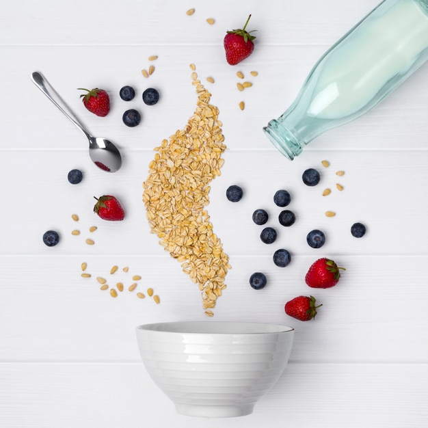 Fraises, myrtilles, pignons de pin et flocons d&#39;avoine coulent dans un bol en céramique pour la cuisson de muesli ou de granola fait maison