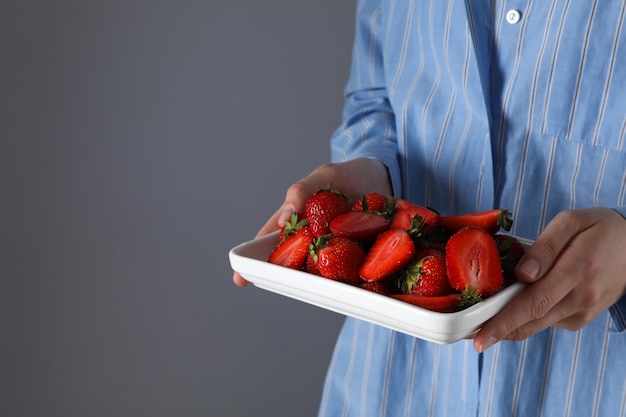 Fraises sur plaque dans les mains des femmes sur fond gris espace pour le texte