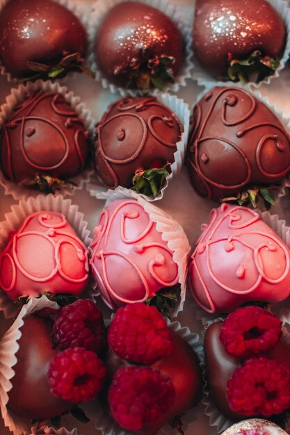 Des fraises recouvertes de chocolat rose avec des framboises fraîches sur le dessus Candy et collection de bonbons