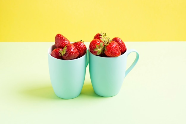 Fraises rouges en cercles bleus sur fond vert clair et citron vert