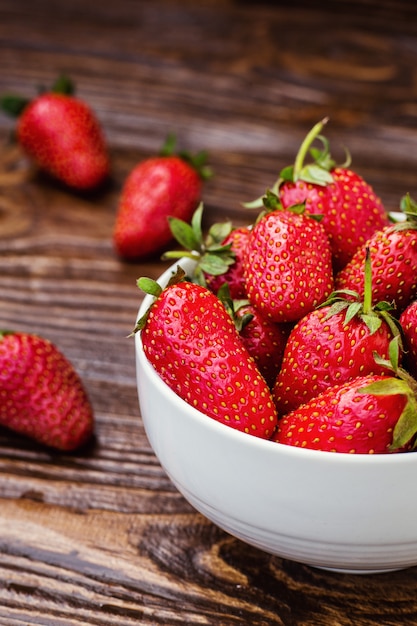 Fraises rouges dans un bol sur un fond en bois