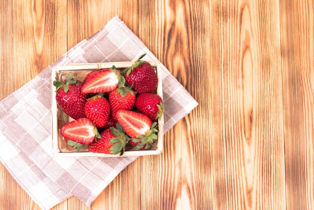 Fraises rouges dans un panier sur un fond en bois