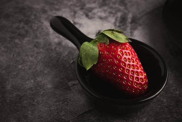 Fraises rouges fraîches dans un bol. Fruits aux fraises sur l'espace de copie de table en pierre sombre pour le texte. vue de dessus.