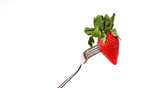 Photo des fraises rouges mûres sur une fourchette sur un fond blanc