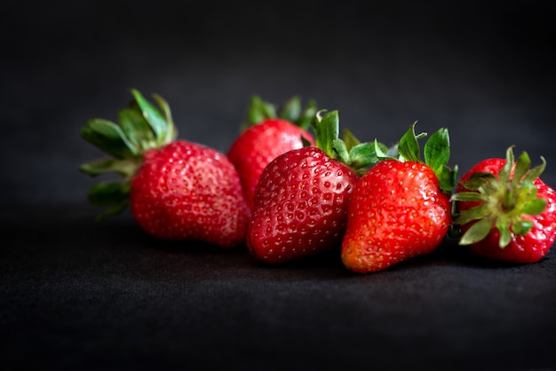 Fraises rouges mûres sur surface noire