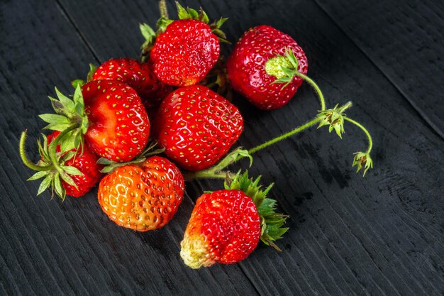 Fraises rouges mûres sur une table antique noire Régime sucré d'été et pack sain de vitamines