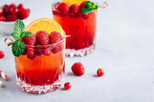 Framboise Cranberry Sangria Punch ou Mojito dans des verres avec des tranches d'orange et de menthe