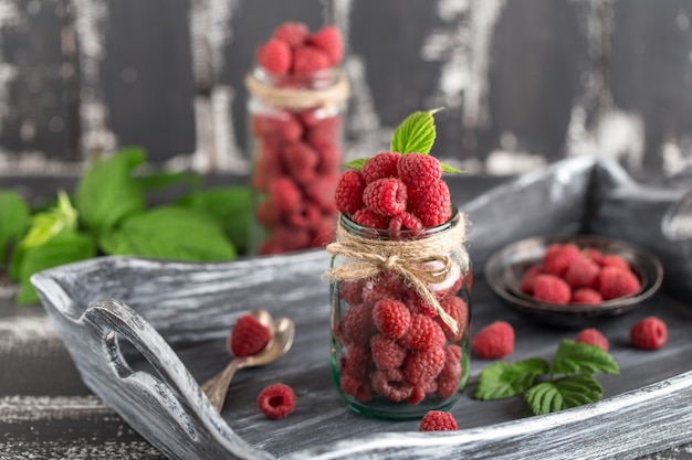 Framboise dans un bocal en verre sur une table en bois foncé. Concept d'aliments sains. Baies fraîches biologiques