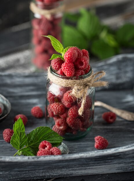 Framboise dans un bocal en verre sur une table en bois foncé. Concept d'aliments sains. Baies fraîches biologiques