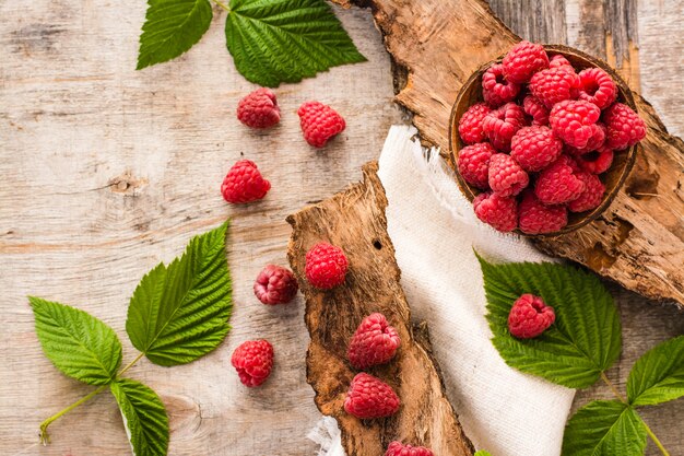 Framboise dans un bol, baies et feuilles sur un bois minable. Vue de dessus