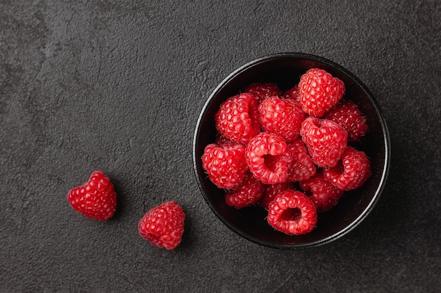 Framboise dans un bol sur fond noir. Nourriture saine. Vue de dessus.