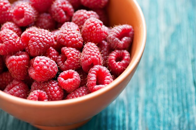 Framboise fraîche dans un bol en céramique sur le bureau rustique en bois bleu