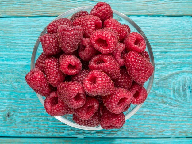 Framboise fraîche dans un bol de verres sur bleu