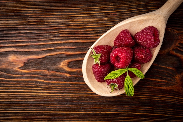 Framboise fraîche dans une cuillère en bois sur fond de bois foncé