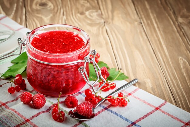 Framboise mûre et confiture de framboise sur une table en bois.