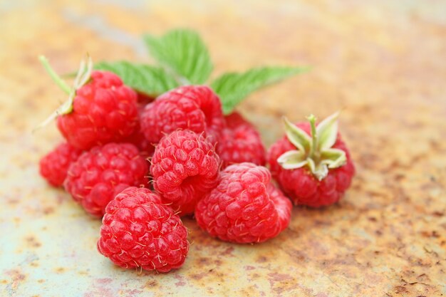 Framboise mûre avec une feuille sur un vieux fond métallique