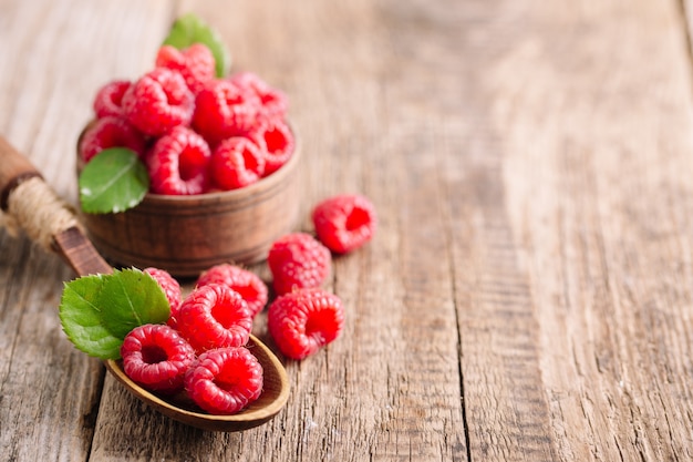 Framboises en assiette et cuillère sur table en bois