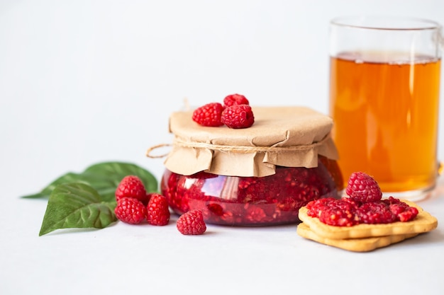 Framboises au sucre, framboises fraîches et saines, confiture maison dans un bocal, petit-déjeuner du matin à la lumière