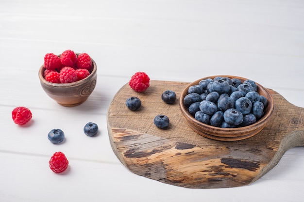 Framboises et bleuets dans de petits bols sur table en bois