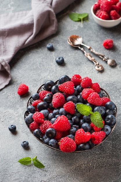 Framboises et bleuets frais dans une assiette sur une surface sombre