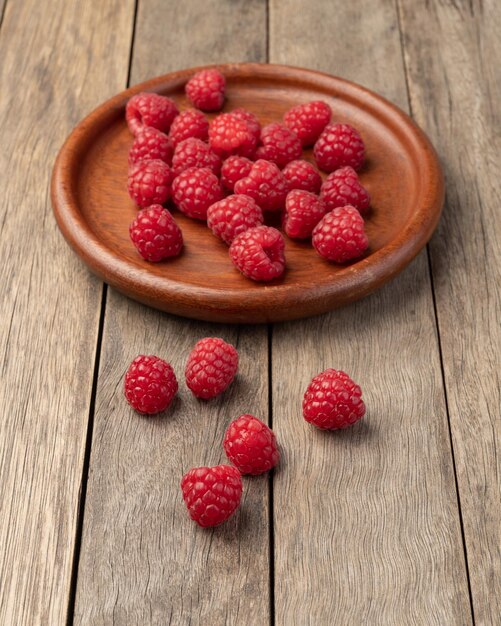 Framboises dans une assiette sur table en bois.