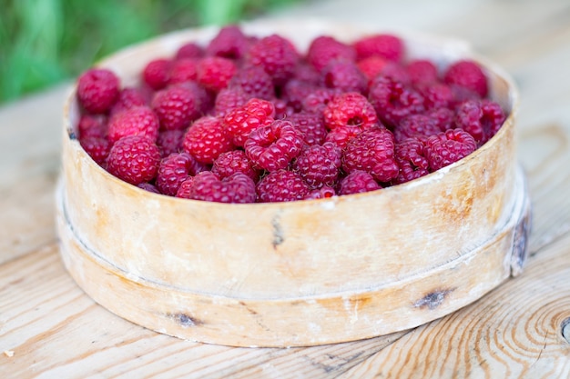 Framboises dans un vieux tamis sur une table en bois