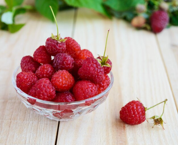 Framboises fraîchement cueillies dans une piala transparente sur un bois clair