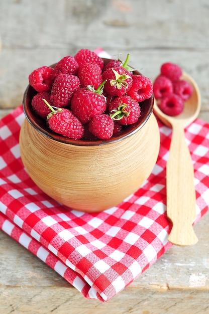 Framboises fraîches en pot d'argile sur fond de bois