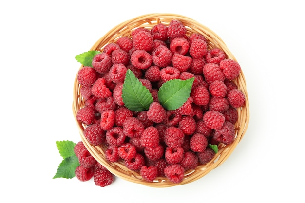 Framboises juteuses rouges dans un vase en osier, isolées sur fond blanc.