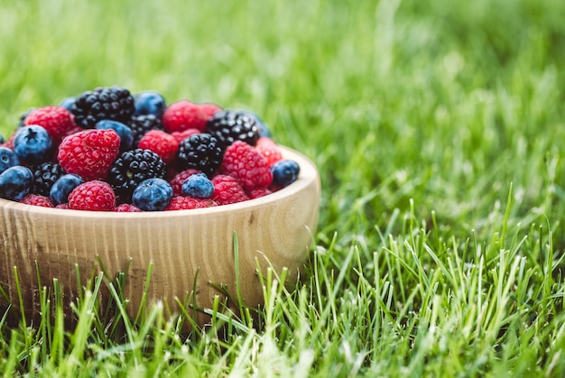 Framboises et mûres dans un bol en bois sur table, vintage