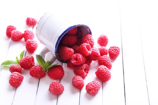 Des framboises mûres dans une tasse sur une table en gros plan