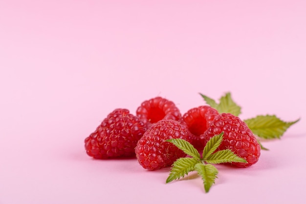 Framboises mûres avec des feuilles de framboise isolées sur une surface blanche