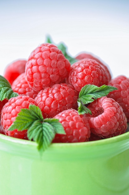 Framboises mûres fraîches dans un bol vert sur un fond en bois Close up