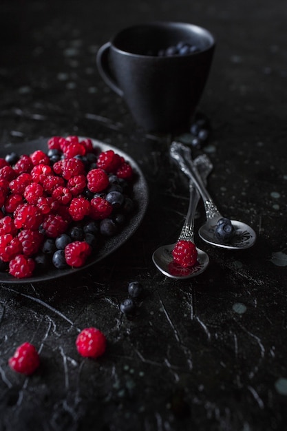 Framboises et myrtilles, sur fond noir, baies sauvages