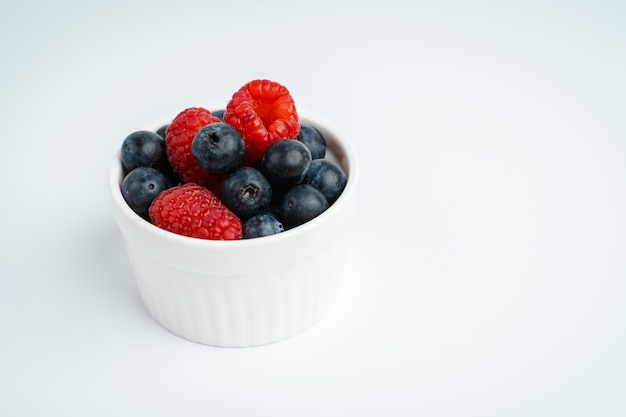 Framboises et myrtilles fraîches dans un bol blanc