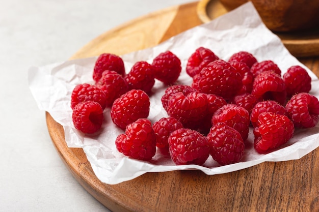 Des framboises sur un papier blanc sur un fond clair.