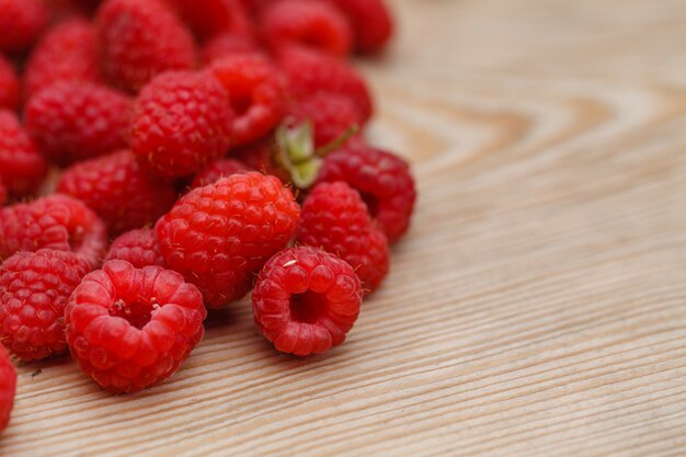 Framboises sucrées mûres sur une surface en bois