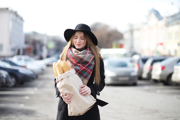 Française avec des baguettes dans le sac à la sortie du magasin