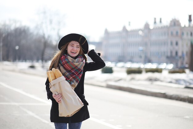 Française avec des baguettes dans le sac à la sortie du magasin