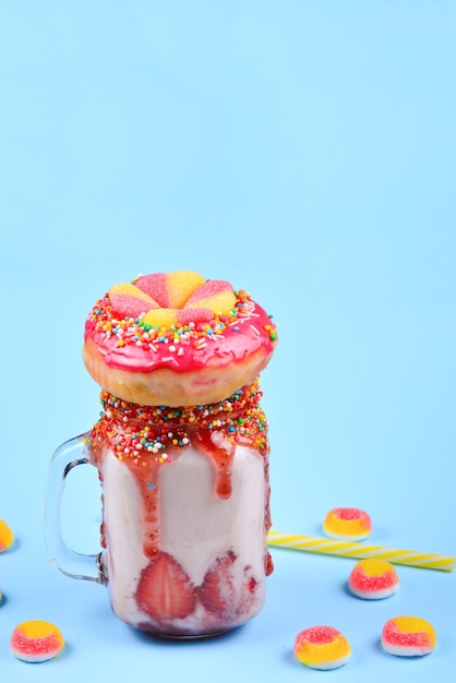 Freakshake. Milk-shake extrême à la fraise, bonbons à la gelée, beignet.