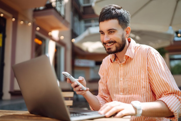 Un freelance heureux souriant en travaillant sur un ordinateur portable avec un téléphone conférence en ligne concept de blog