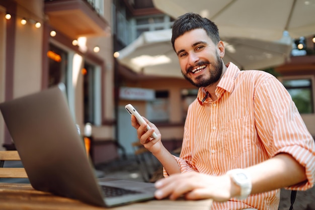 Un freelance heureux souriant en travaillant sur un ordinateur portable avec un téléphone conférence en ligne concept de blog