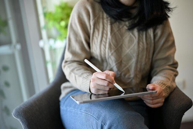 Freelancer asiatique utilisant sa tablette tout en se relaxant dans le café image recadrée