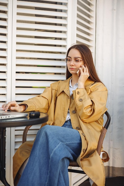 Freelancer féminin sérieux parlant au téléphone portable tout en naviguant sur un ordinateur portable