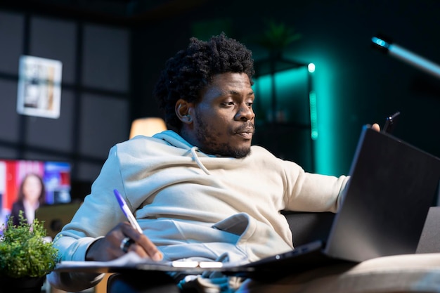 Freelancer travaillant à domicile en écrivant des idées d'affaires sur un bloc-notes